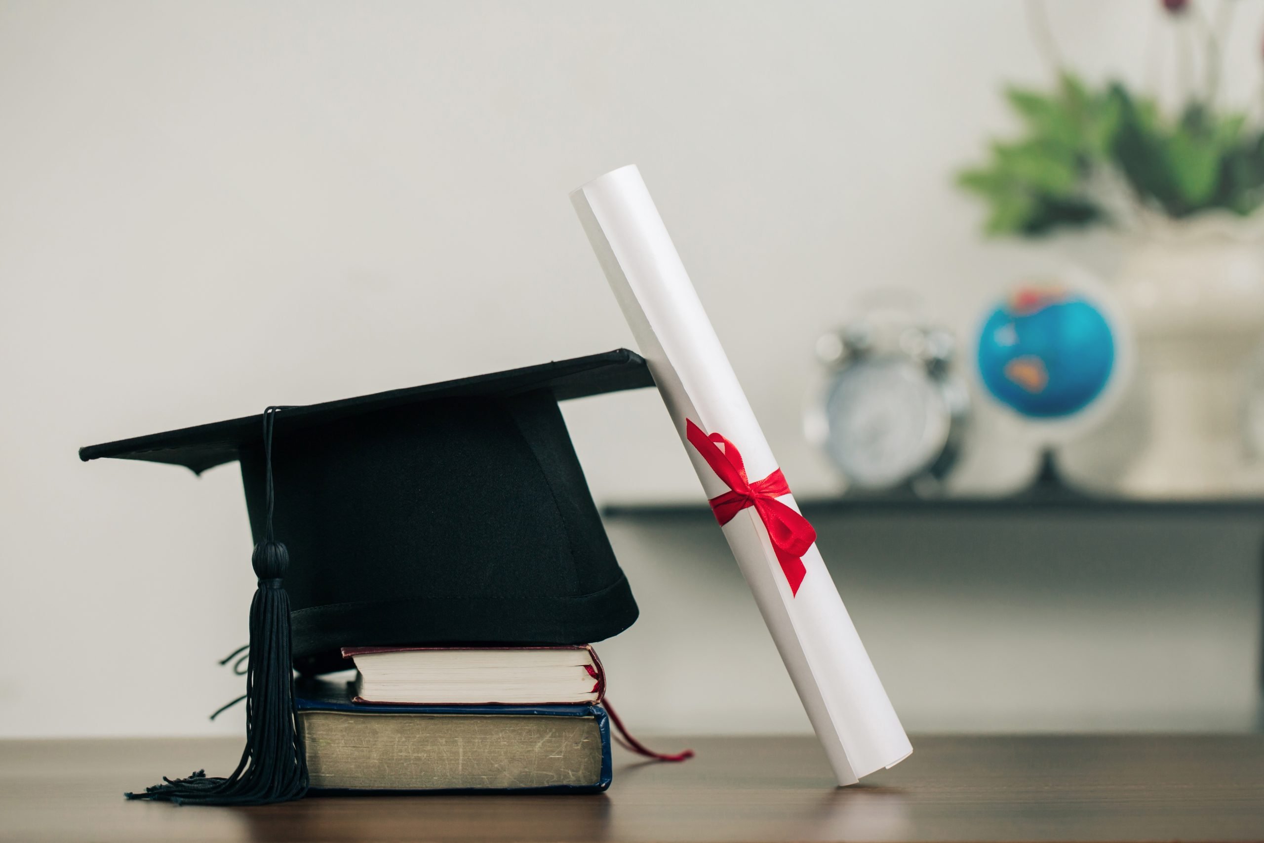 A mortarboard on books and a graduation scroll on the desk.education learning concept